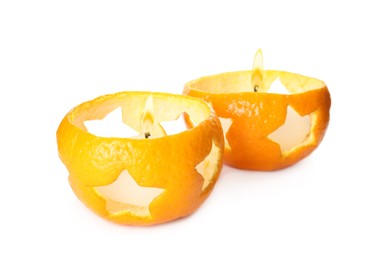 Candles in tangerine peels as holders on white background