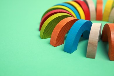Photo of Colorful wooden pieces of play set on green background, closeup with space for text. Educational toy for motor skills development