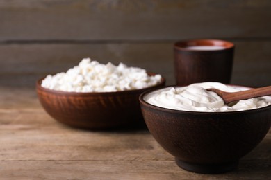 Photo of Clay bowl with sour cream and spoon on wooden table, space for text