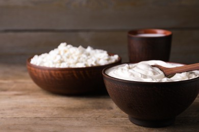 Clay bowl with sour cream and spoon on wooden table, space for text