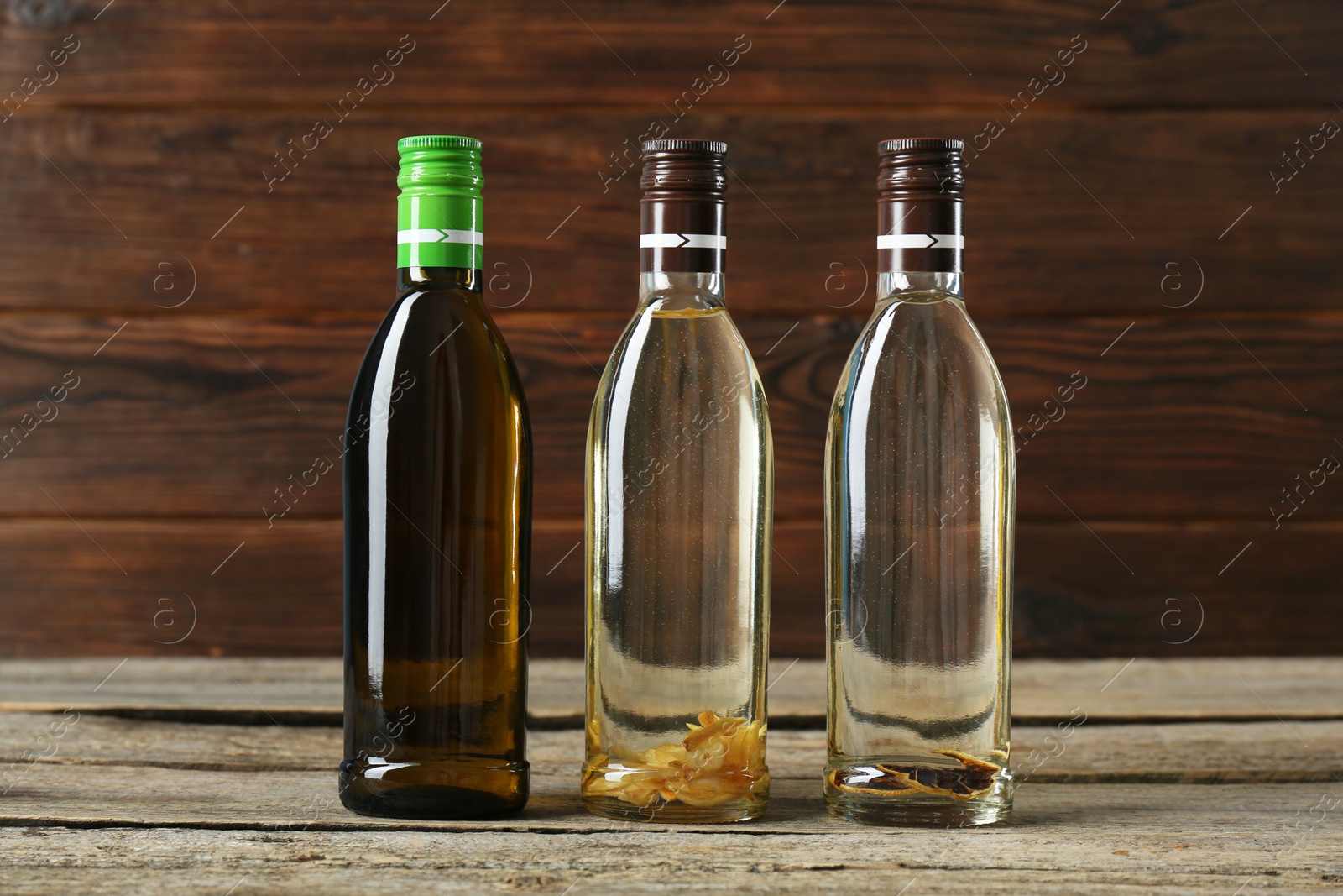 Photo of Vegetable fats. Different cooking oils in glass bottles on wooden table