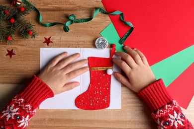 Little child making Christmas card at wooden table, top view