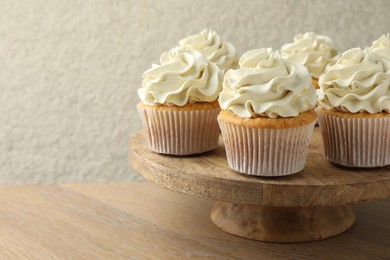 Photo of Tasty vanilla cupcakes with cream on wooden table, space for text