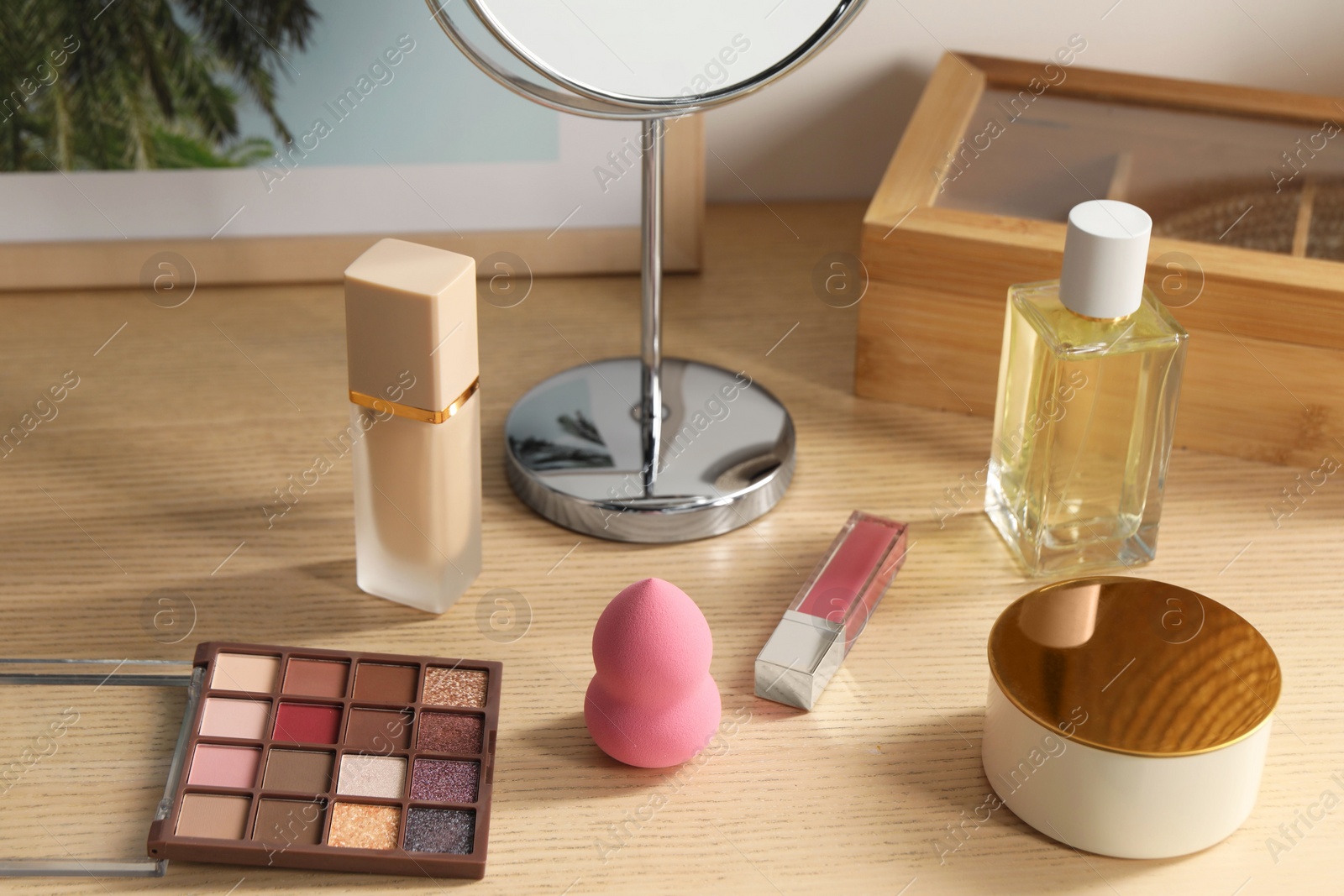 Photo of Makeup products and perfume on wooden dressing table