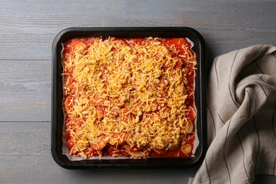 Photo of Tasty parsnips with sauce and grated cheese on grey wooden table, top view