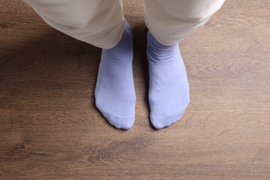 Photo of Woman in stylish purple socks standing on wooden floor, top view