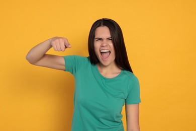Photo of Aggressive young woman pointing on orange background