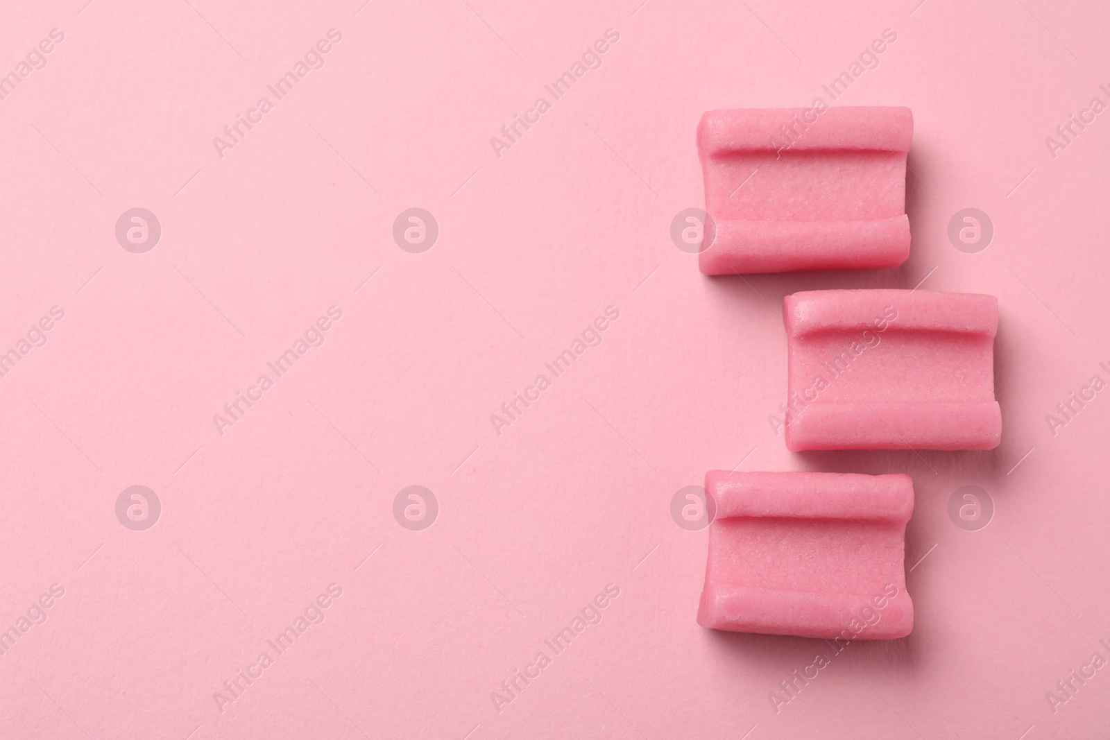 Photo of Tasty chewing gums on pink background, flat lay. Space for text