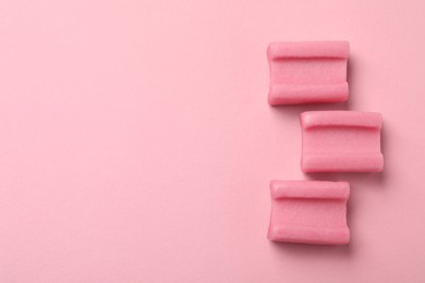 Photo of Tasty chewing gums on pink background, flat lay. Space for text