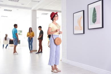 Young woman with glass of champagne at exhibition in art gallery