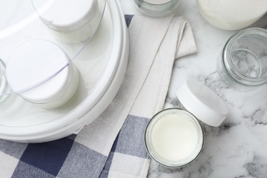 Photo of Modern yogurt maker and jars on white marble table, flat lay