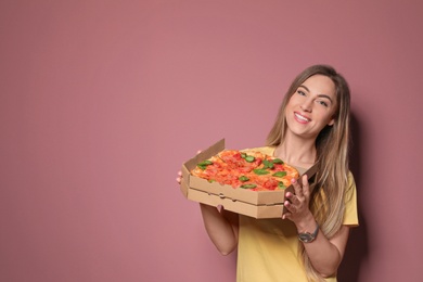 Photo of Attractive young woman with delicious pizza on color background