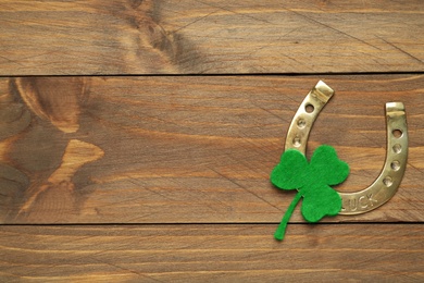 Photo of Decorative clover leaf and horseshoe on wooden background, flat lay with space for text. St. Patrick's Day celebration