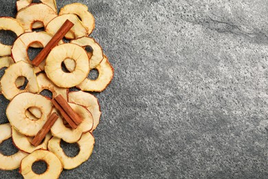 Delicious apple chips and cinnamon on grey table, flat lay. Space for text