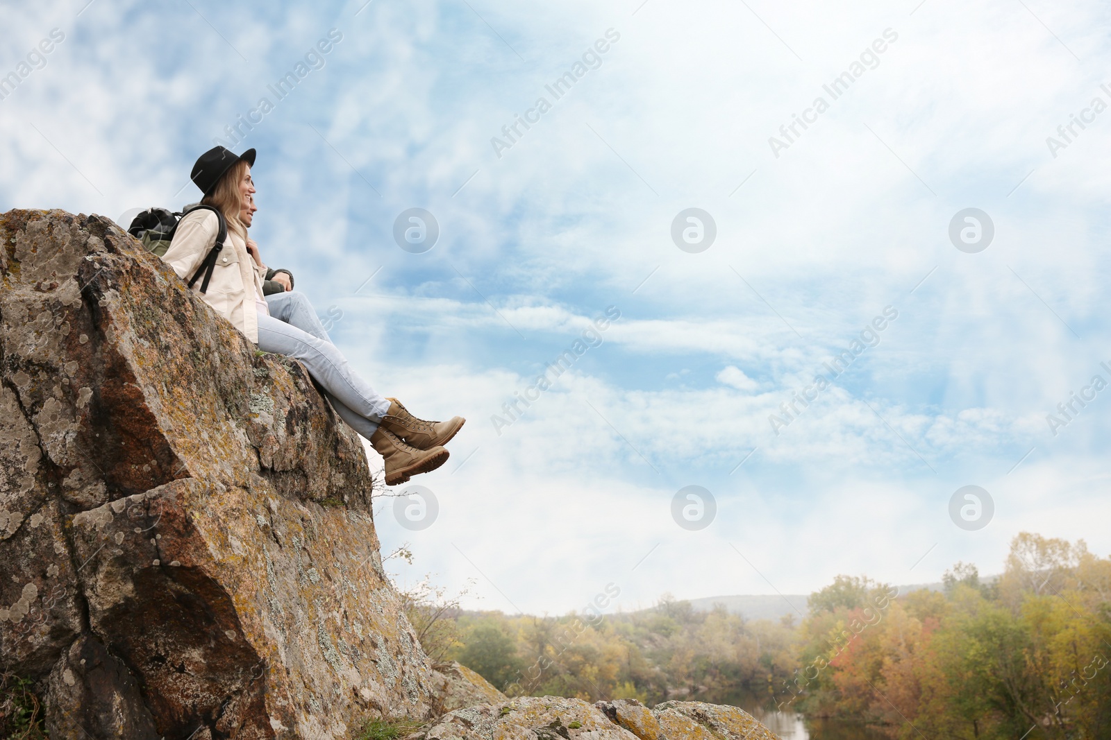 Photo of Couple of hikers sitting on steep cliff outdoors