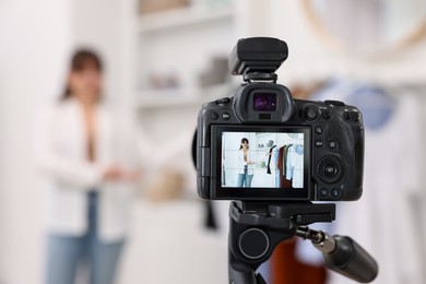 Fashion blogger showing her clothes while recording video at home, focus on camera