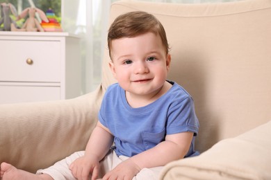 Photo of Happy baby boy sitting in armchair at home