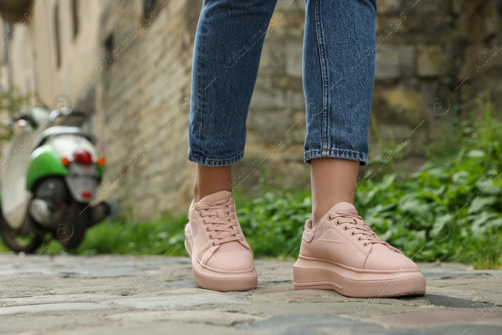 Photo of Woman in stylish sneakers walking on city street, closeup