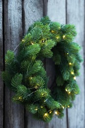 Photo of Beautiful Christmas wreath with string lights hanging on wooden wall