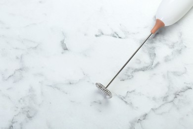 Photo of Milk frother wand on white marble table, top view. Space for text