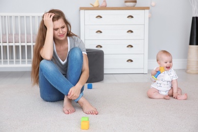 Young mother suffering from postnatal depression and cute baby girl at home