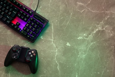Modern RGB keyboard and game pad on grey table, flat lay. Space for text
