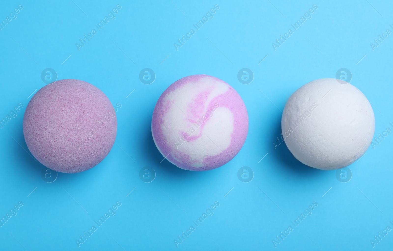 Photo of Colorful bath bombs on light blue background, flat lay