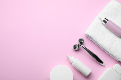 Photo of Metal face roller, cosmetic products and towel on pink background, flat lay. Space for text