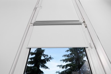 Window with white roller blinds indoors, low angle view