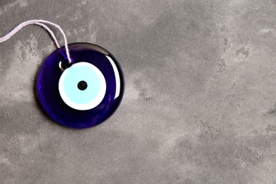 Photo of Evil eye amulet on grey table, top view. Space for text