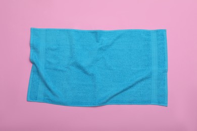 Photo of Crumpled light blue beach towel on pink background, top view
