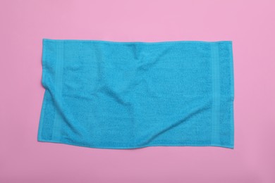 Crumpled light blue beach towel on pink background, top view