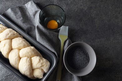 Photo of Homemade braided bread and ingredients on grey table, flat lay with space for text. Cooking traditional Shabbat challah