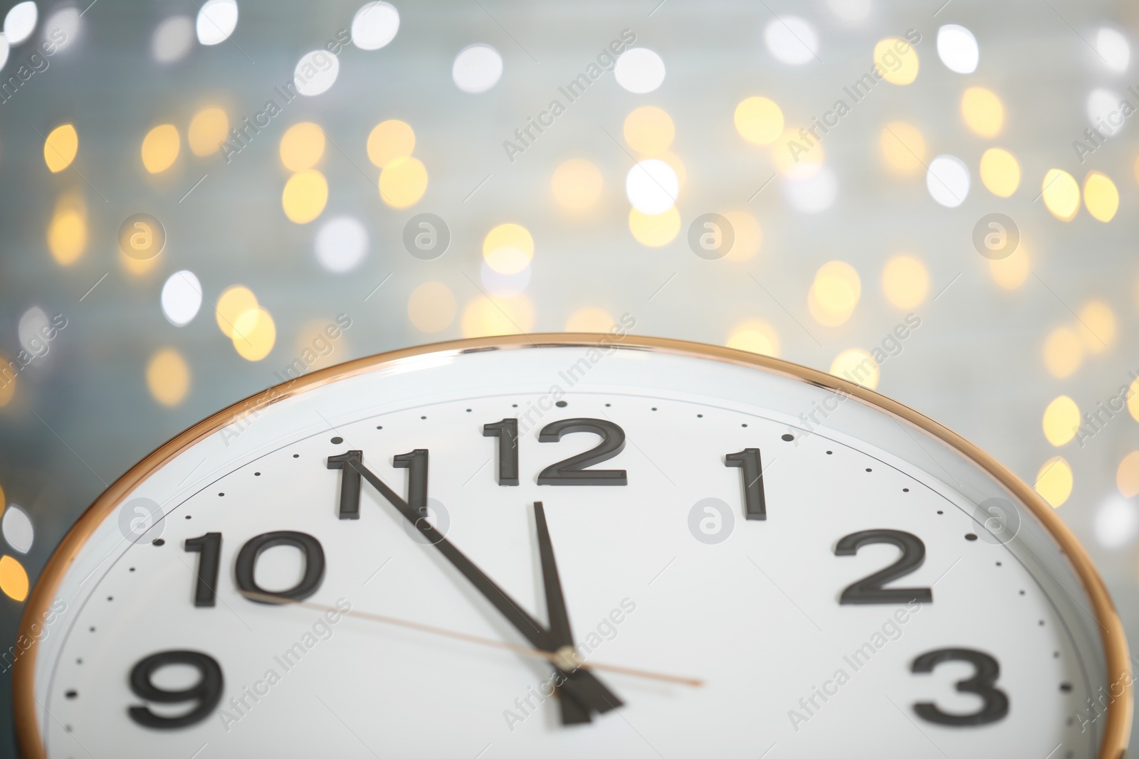 Photo of Clock showing five minutes until midnight on blurred background, closeup. New Year countdown