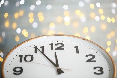 Clock showing five minutes until midnight on blurred background, closeup. New Year countdown