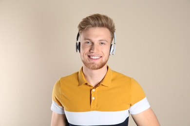 Handsome young man listening to music with headphones on color background