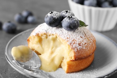 Photo of Tasty vanilla fondant with white chocolate and blueberries on grey table, closeup