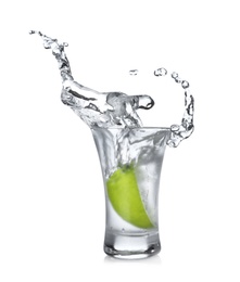 Photo of Lime slice falling into shot glass of vodka on white background