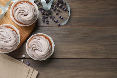 Photo of Tasty cupcakes on wooden table, flat lay. Space for text