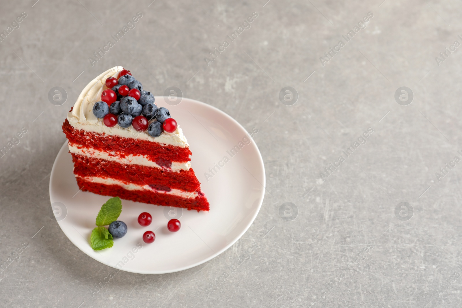 Photo of Plate with piece of delicious homemade red velvet cake and space for text on table