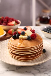 Photo of Delicious pancakes with fresh berries, butter and honey on white marble table, closeup