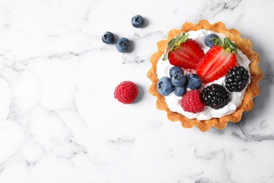 Photo of Top view of tart with different berries on marble table, space for text. Delicious pastries