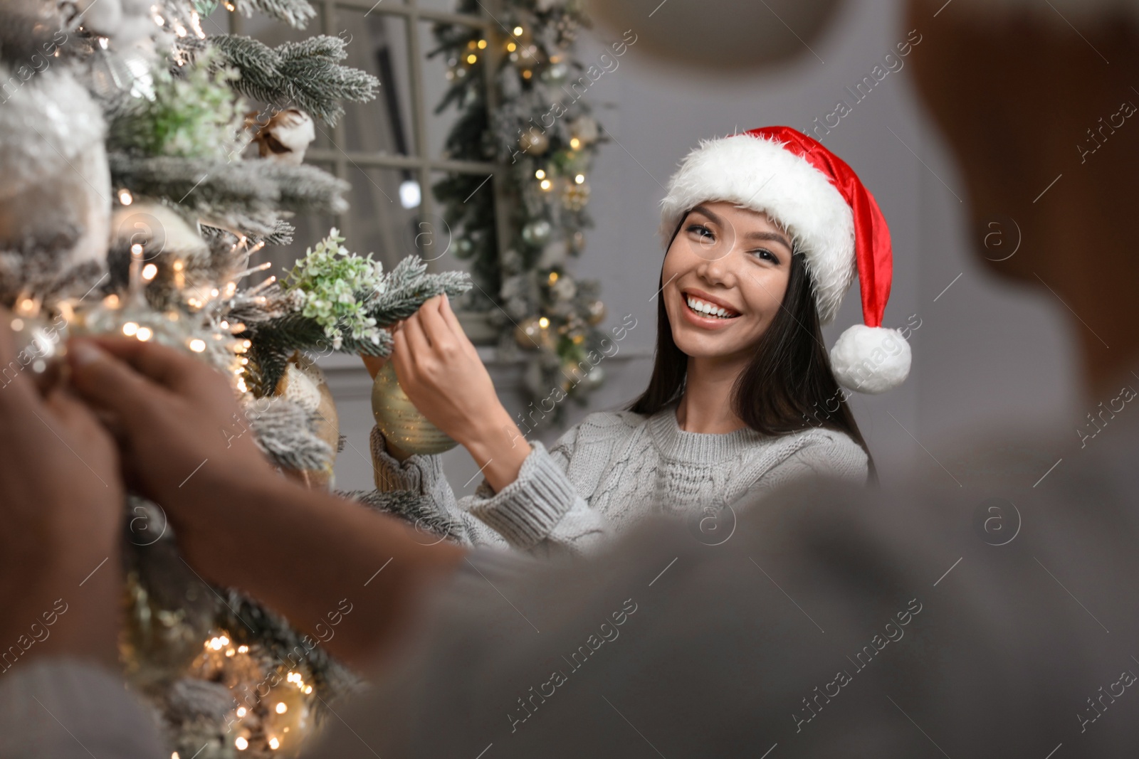 Photo of Happy young couple decorating Christmas tree together at home