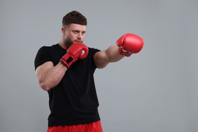 Photo of Man in boxing gloves fighting on grey background