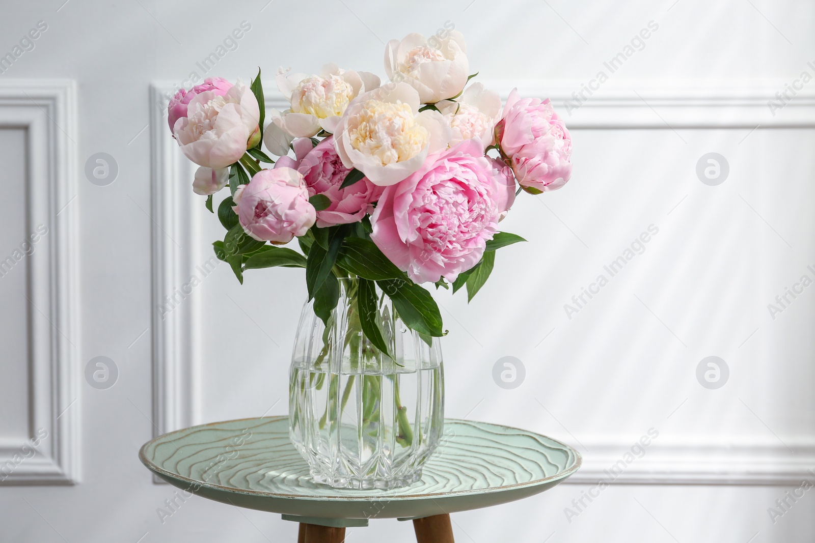 Photo of Beautiful peonies in glass vase on table