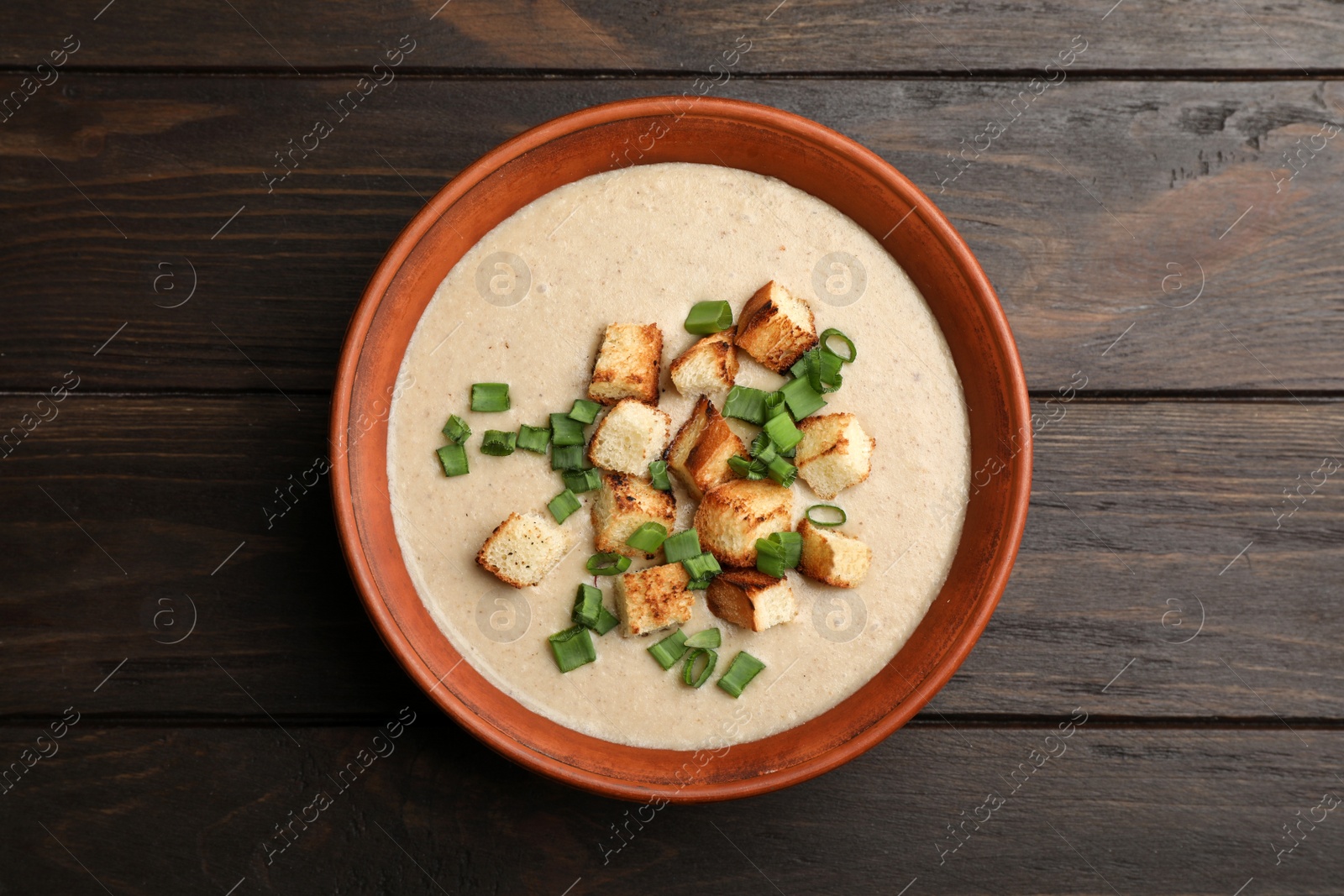 Photo of Bowl of fresh homemade mushroom soup on wooden background, top view