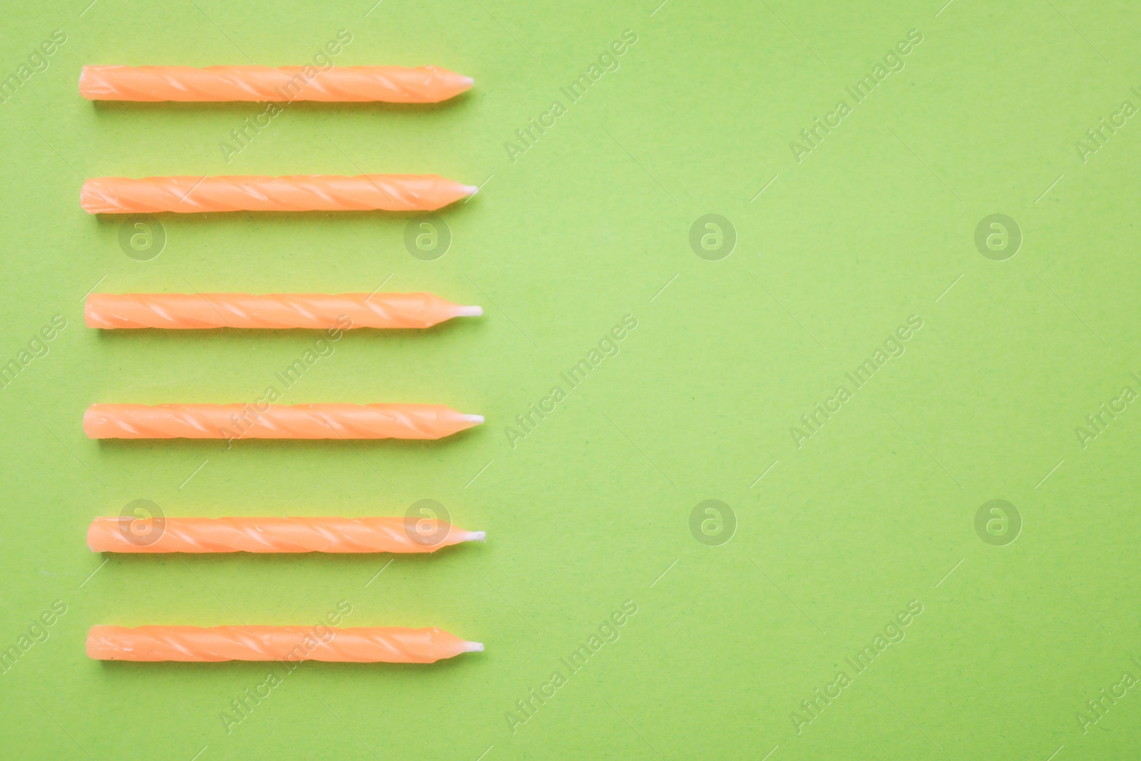 Photo of Orange birthday candles on green background, top view with space for text