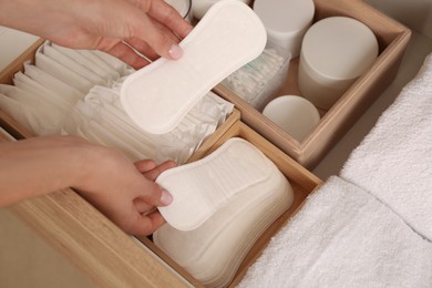 Photo of Young woman putting pantyliners into drawer, closeup