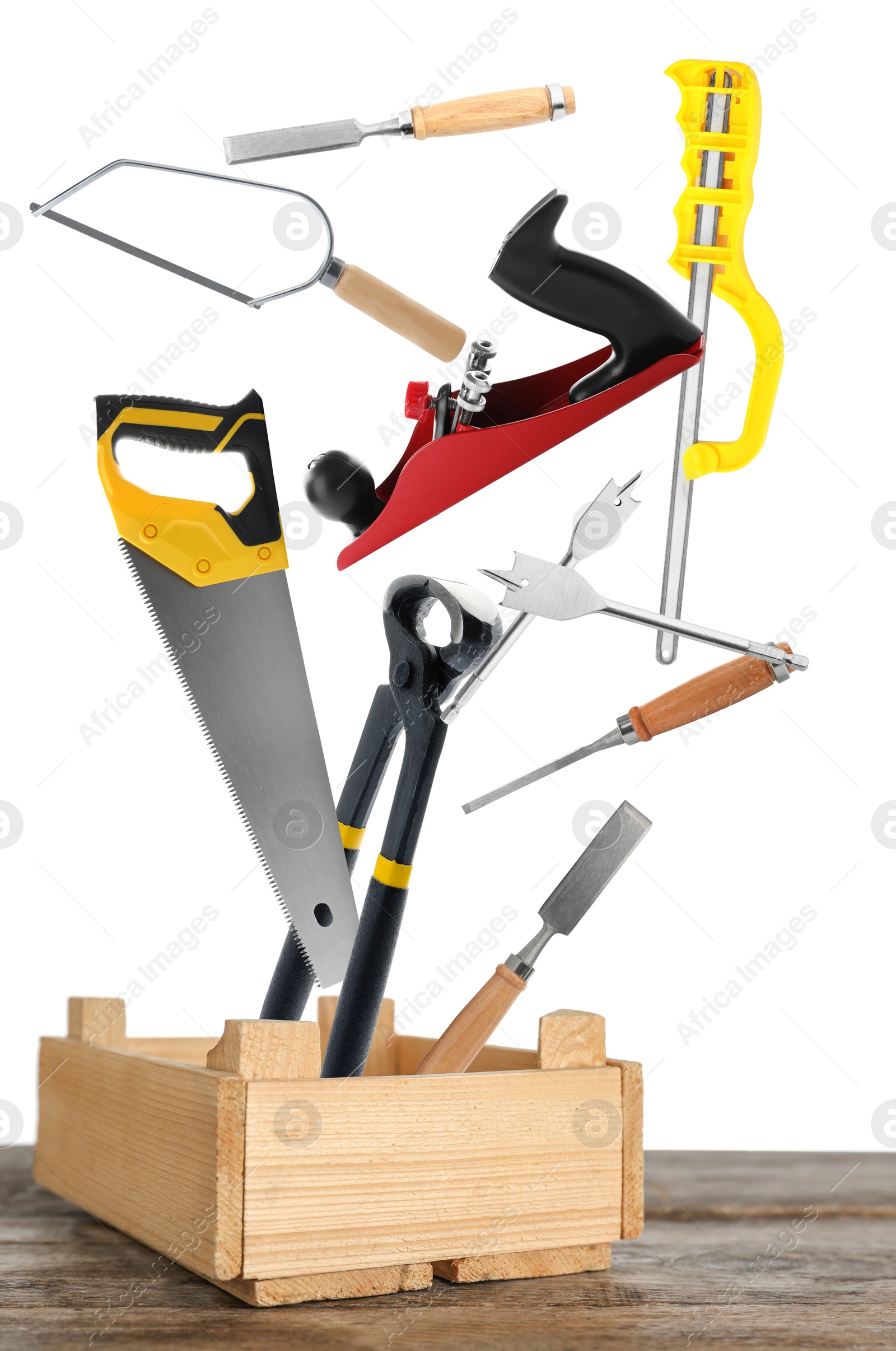 Image of Different carpenter's tools falling into wooden box on white background