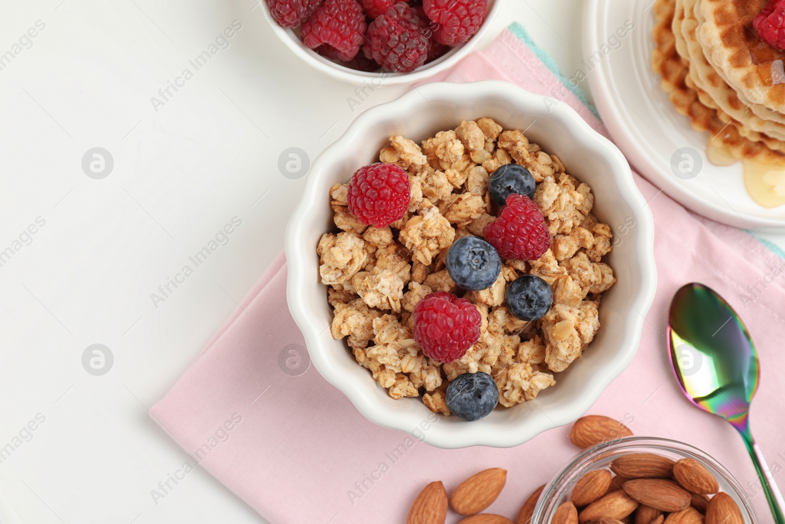 Photo of Healthy breakfast with granola and berries served on white table, flat lay. Space for text